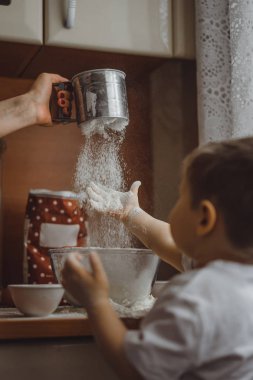 Mutfakta küçük çocuk anne pişirmek için yardımcı olur. Çocuk pişirme ilgilenmektedir.