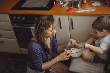 Mutfakta küçük çocuk anne pişirmek için yardımcı olur. Çocuk pişirme ilgilenmektedir.