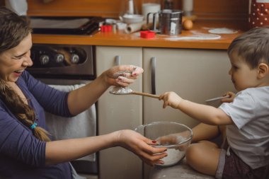 Mutfakta küçük çocuk anne pişirmek için yardımcı olur. Çocuk pişirme ilgilenmektedir.