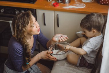 Mutfakta küçük çocuk anne pişirmek için yardımcı olur. Çocuk pişirme ilgilenmektedir.