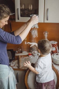 Mutfakta küçük çocuk anne pişirmek için yardımcı olur. Çocuk pişirme ilgilenmektedir.