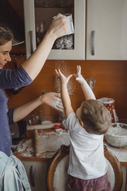 Mutfakta küçük çocuk anne pişirmek için yardımcı olur. Çocuk pişirme ilgilenmektedir.