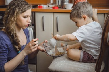 Mutfakta küçük çocuk anne pişirmek için yardımcı olur. Çocuk pişirme ilgilenmektedir.