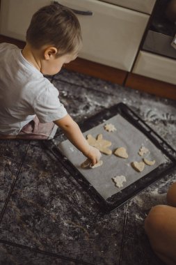 Mutfakta küçük çocuk anne pişirmek için yardımcı olur. Çocuk pişirme ilgilenmektedir.