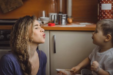 Mutfakta küçük çocuk anne pişirmek için yardımcı olur. Çocuk pişirme ilgilenmektedir.