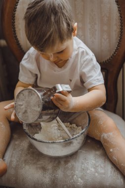 Mutfakta küçük çocuk anne pişirmek için yardımcı olur. Çocuk pişirme ilgilenmektedir.