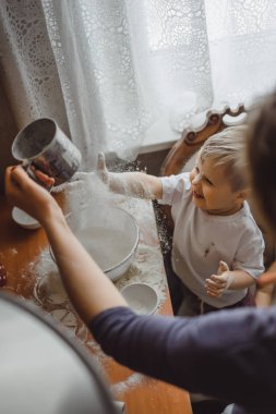 Mutfakta küçük çocuk anne pişirmek için yardımcı olur. Çocuk pişirme ilgilenmektedir.