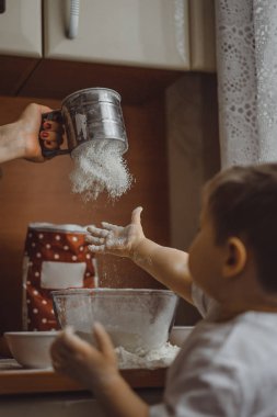Mutfakta küçük çocuk anne pişirmek için yardımcı olur. Çocuk pişirme ilgilenmektedir.