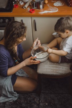 Mutfakta küçük çocuk anne pişirmek için yardımcı olur. Çocuk pişirme ilgilenmektedir.