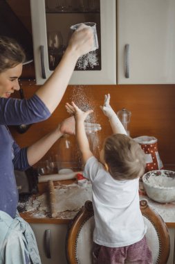 Mutfakta küçük çocuk anne pişirmek için yardımcı olur. Çocuk pişirme ilgilenmektedir.