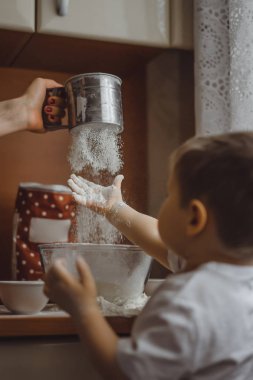 Mutfakta küçük çocuk anne pişirmek için yardımcı olur. Çocuk pişirme ilgilenmektedir.
