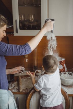 Mutfakta küçük çocuk anne pişirmek için yardımcı olur. Çocuk pişirme ilgilenmektedir.