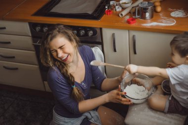 Mutfakta küçük çocuk anne pişirmek için yardımcı olur. Çocuk pişirme ilgilenmektedir.