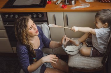Mutfakta küçük çocuk anne pişirmek için yardımcı olur. Çocuk pişirme ilgilenmektedir.