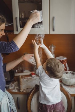 Mutfakta küçük çocuk anne pişirmek için yardımcı olur. Çocuk pişirme ilgilenmektedir.