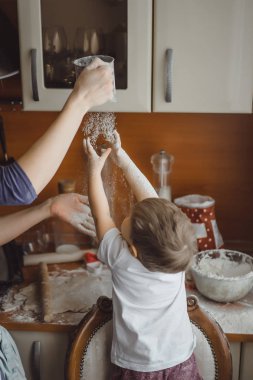 Mutfakta küçük çocuk anne pişirmek için yardımcı olur. Çocuk pişirme ilgilenmektedir.