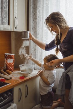 Mutfakta küçük çocuk anne pişirmek için yardımcı olur. Çocuk pişirme ilgilenmektedir.
