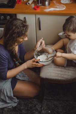 Mutfakta küçük çocuk anne pişirmek için yardımcı olur. Çocuk pişirme ilgilenmektedir.