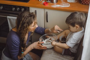 Mutfakta küçük çocuk anne pişirmek için yardımcı olur. Çocuk pişirme ilgilenmektedir.