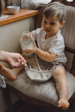 Mutfakta küçük çocuk anne pişirmek için yardımcı olur. Çocuk pişirme ilgilenmektedir.