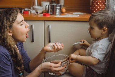 Mutfakta küçük çocuk anne pişirmek için yardımcı olur. Çocuk pişirme ilgilenmektedir.