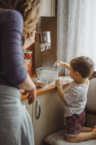 little boy in the kitchen helps mom to cook. the child is involved in cooking.