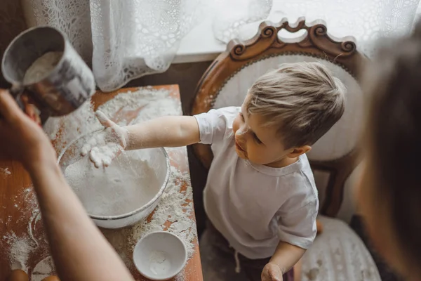 Mutfakta küçük çocuk anne pişirmek için yardımcı olur. Çocuk pişirme ilgilenmektedir.