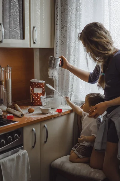little boy in the kitchen helps mom to cook. the child is involved in cooking.