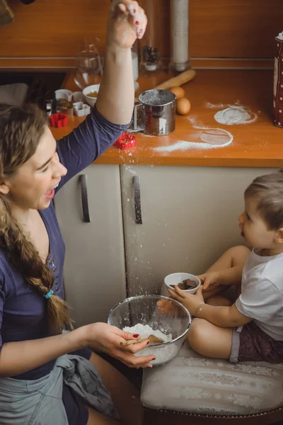 Mutfakta küçük çocuk anne pişirmek için yardımcı olur. Çocuk pişirme ilgilenmektedir.