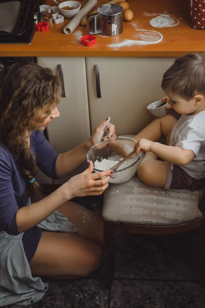 Mutfakta küçük çocuk anne pişirmek için yardımcı olur. Çocuk pişirme ilgilenmektedir.