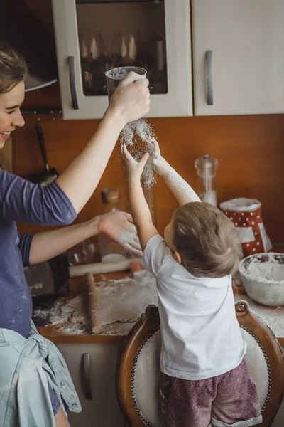 Mutfakta küçük çocuk anne pişirmek için yardımcı olur. Çocuk pişirme ilgilenmektedir.