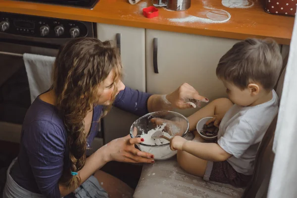 Mutfakta küçük çocuk anne pişirmek için yardımcı olur. Çocuk pişirme ilgilenmektedir.