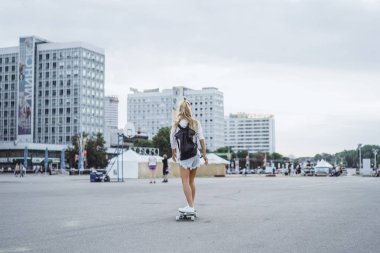 uzun saçlı kız bir kaykay üzerinde kaymaktadır. Sokak, aktif spor