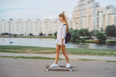 uzun saçlı kız bir kaykay üzerinde kaymaktadır. Sokak, aktif spor