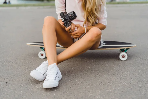 girl with long hair with skateboard photographing on camera. street, active sports