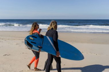 Erkek ve kadın sörf tahtaları ile okyanusa gidin. Erkek ve kız sörf, Portekiz, Nazar gidin. Islati takım elbiseyle sörf.
