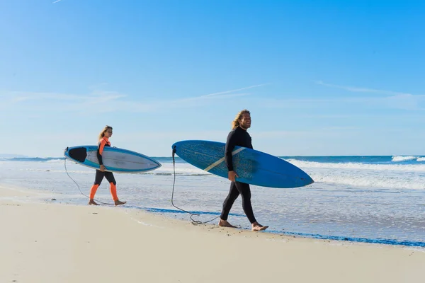 man and woman go to the ocean with surf boards. man and girl go surfing, Portugal, Nazar. Surfing in a wet suit.