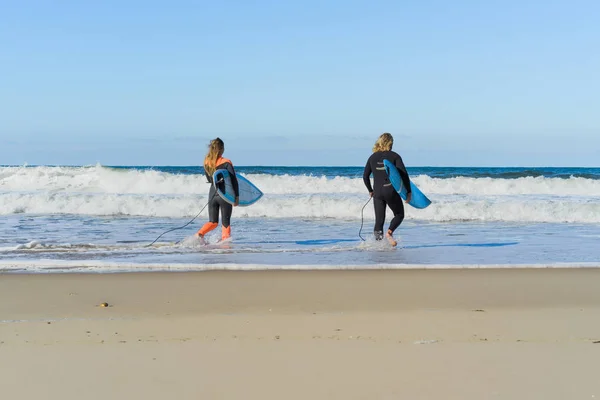 男女はサーフボードを持って海に行きます 男と女の子はサーフィンに行く ポルトガル ナザール ウェットスーツでサーフィン — ストック写真