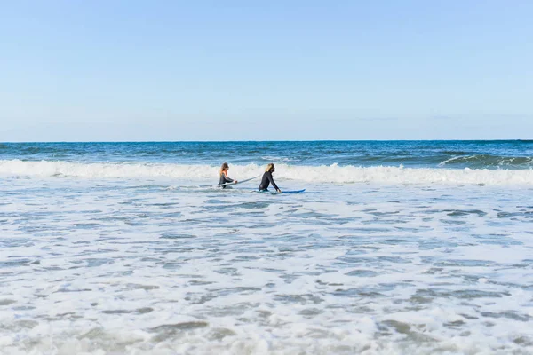 男女はサーフボードを持って海に行きます 男と女の子はサーフィンに行く ポルトガル ナザール ウェットスーツでサーフィン — ストック写真