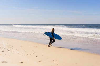 okyanus kıyısında sörf tahtası olan adam. Sörfçü ıslak elbiseli. Nazare, Portekiz.