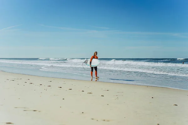 Nazar ポルトガルのサーフボードとウェット スーツで海の海岸にサーフィン女の子 — ストック写真