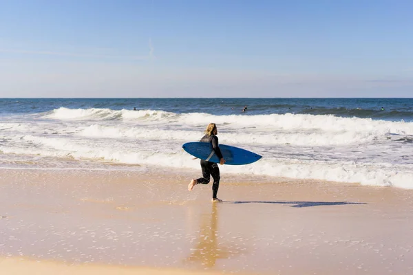 man with surf board on the ocean shore. Surfer in a wet suit. Nazare, Portugal.