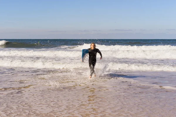 man with surf board on the ocean shore. Surfer in a wet suit. Nazare, Portugal.