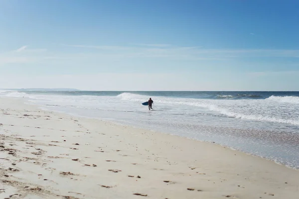 man with surf board on the ocean shore. Surfer in a wet suit. Nazare, Portugal.