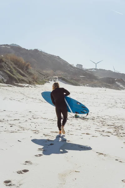 man with surf board on the ocean shore. Surfer in a wet suit. Nazare, Portugal.