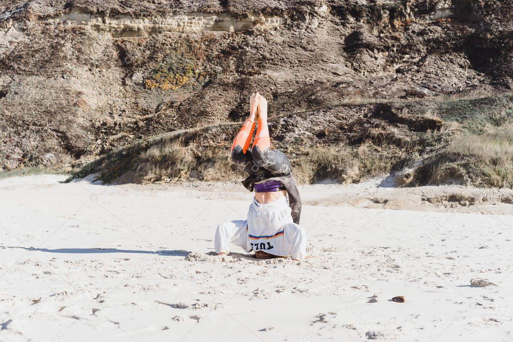 girl doing yoga on the beach, stand on her head.