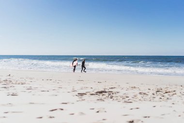 okyanusta bir öğrenci ile sörf eğitmeni. Eğitim tahtası olan ıslak takım elbiseli sörfçü. Nazare, Portekiz.