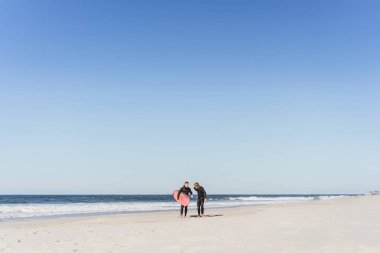 okyanusta bir öğrenci ile sörf eğitmeni. Eğitim tahtası olan ıslak takım elbiseli sörfçü. Nazare, Portekiz.