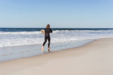 Palet ve okyanus kıyısında hidro elbiseli bir bodyboard sörfçü