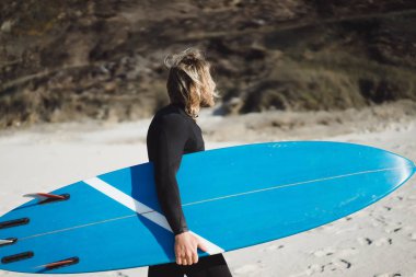 Palet ve okyanus kıyısında hidro elbiseli bir bodyboard sörfçü